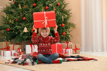 Obraz na płótnie Canvas Little child with gift box on floor near Christmas tree at home