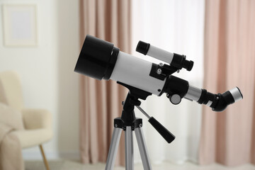 Tripod with modern telescope in stylish room, closeup