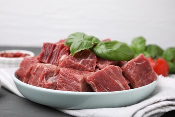Cut fresh beef meat with basil leaves on table, closeup