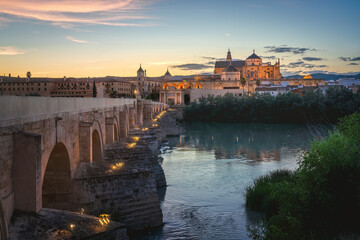 Illuminated Cordoba Skyline at sunset with Cathedral, Roman Bridge and Guadalquivir River -...
