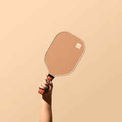 Female Hand Holding Pickleball Paddle on solid backdrop