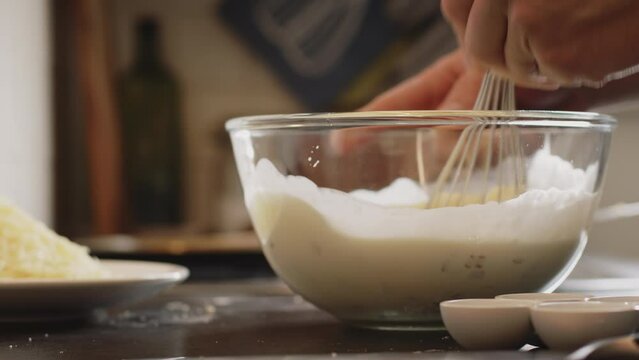 Home cooking - a man making batter mix for quiche Lorraine. Low angle closeup shot.