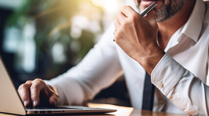 Businessman consulting his laptop and holding his smartphone with another hand because he is waiting for an urgent call.