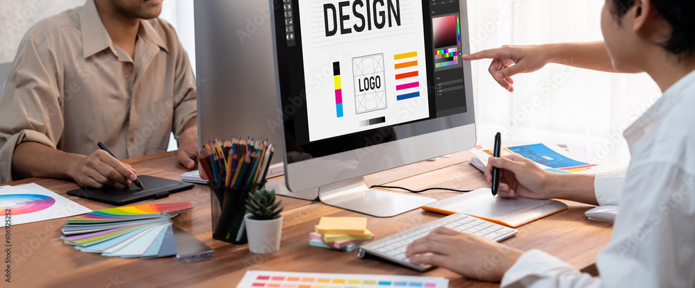 Poster Graphic designer work on computer laptop and with graphic drawing pen while brainstorming unique design with professional graphic team in modern digital studio workplace. Panorama shot. Scrutinize