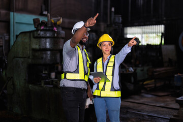 Engineer and manager look at tablet checking the maintenance part and pointing to storage location
