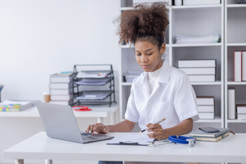 Happy doctor Portrait of young African American woman nurse or doctor smilingusing a laptop writing content at consultation