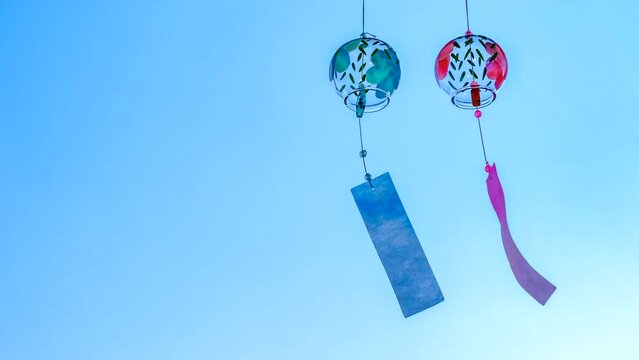 日本のガラス製の手作り風鈴が青空の下で揺れている　左に空間