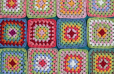 Handmade crocheting, needlework and handicraft concept. Rainbow colored granny squares close up photo. Crochet texture. 
