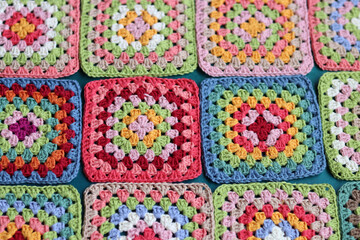 Handmade crocheting, needlework and handicraft concept. Rainbow colored granny squares close up photo. Crochet texture. 
