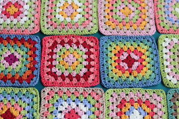 Handmade crocheting with colorful threads and scissors on grey background