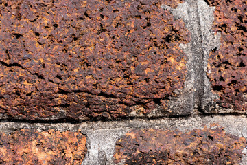 The dark brown red brick wall looks like an ancient wall.