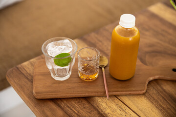 Healthy turmeric and ginger roots drink with lime in a glass on wooden desk.