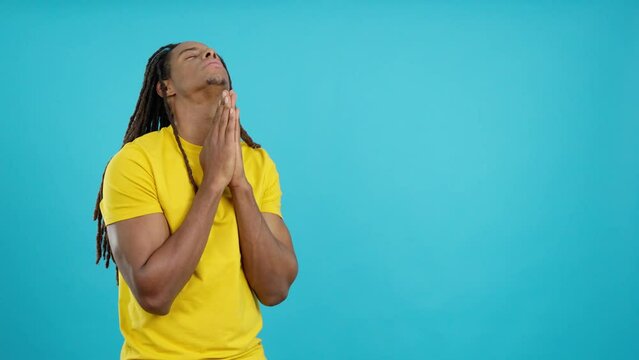 Latin man with dreadlocks praying with eyes closed