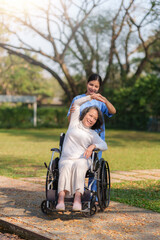 Asian nurse or physiotherapist caring for elderly woman sitting wheelchair. Asian female nurse takes care of patients and takes them for a walk in the hospital park.