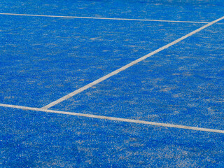 Fototapeta na wymiar Detail of a new synthetic tennis court. White lines on a blue artificial grass tennis court. Racket sports concept