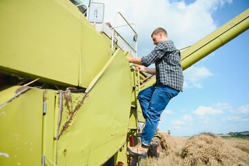 Harvester machine driver climbing into a cab to harvest his wheat field. Farmer getting in combine...