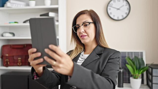 Middle eastern woman business worker combing hair with hand make selfie by touchpad at office