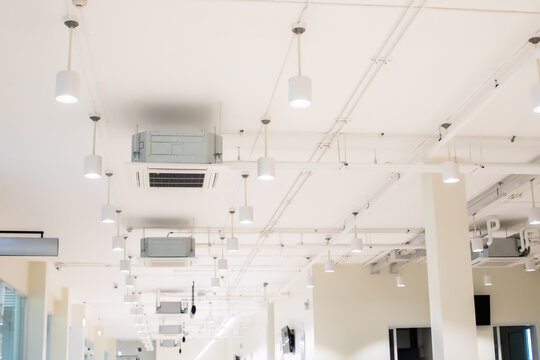 Ceiling mounted cassette type air condition units with other parts of ventilation system with hanging lights and other construction parts.
