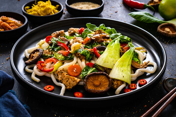 Chicken nuggets with noodles and stir fried vegetables on black table
