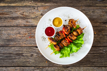 Meat skewers - grilled meat with vegetables on wooden background

