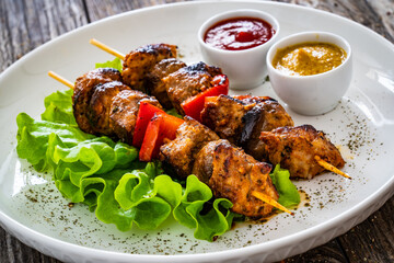 Meat skewers - grilled meat with vegetables on wooden background
