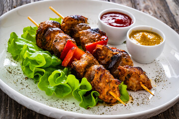 Meat skewers - grilled meat with vegetables on wooden background
