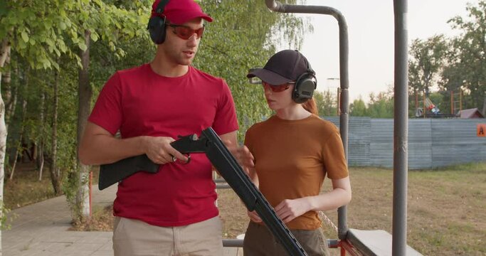 Skeet Shooting Sport. couple is interested in shooting skeet for fun or sport slow motion. Sportsmanship. handsome caucasian man and young woman checking details of weapon before training loading gun