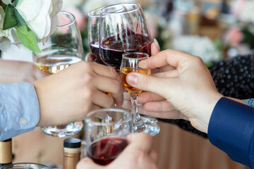 Hands of people clinking glasses with red and white wine in restaurant
