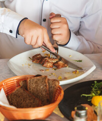 chef in a white uniform cuts meat with a knife in a restaurant