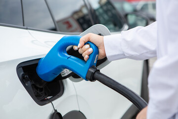 Young business woman refueling her electric car at a EV charging station. Concept of environmentally friendly vehicle. Electric car concept. Green travelling.