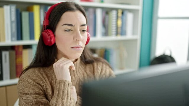 Young beautiful hispanic woman student using computer and headphones at university classroom