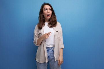 inspired smart brunette young woman in a stylish look owns information on a blue background with copy space