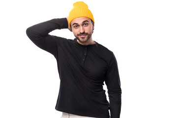 successful 30s authentic brunet male adult in black sweater and yellow cap on white background with...