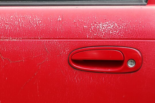 Old red door handle car. Weather-induced variations on the car door.