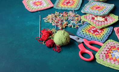 Handmade crocheting, needlework and handicraft concept. Rainbow colored granny squares close up photo. Crochet texture. 