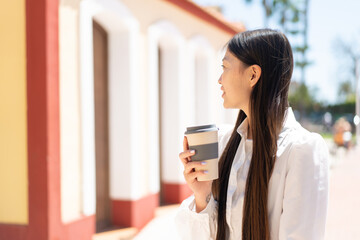 Obraz na płótnie Canvas Pretty Chinese woman at outdoors holding a take away coffee