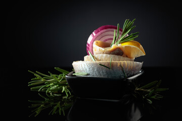 Herring fillet in oil with lemon, red onion, and rosemary.