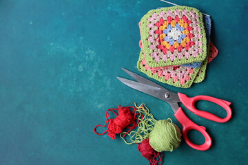 Multicolored Afghan squares, cotton yarn and crochet hook on vibrant blue background with copy...