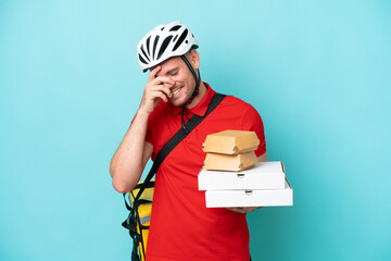 Young caucasian man with thermal backpack and holding fast food isolated on blue background laughing