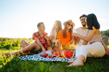 Group of young people gathered in garden for picnic. Friends have fun and  drink beer. Vacation, picnic, friendship or holliday concept.