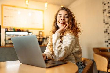 Fototapeta premium Young woman with laptop in cafe. Business, blogging, freelancing, education concept.