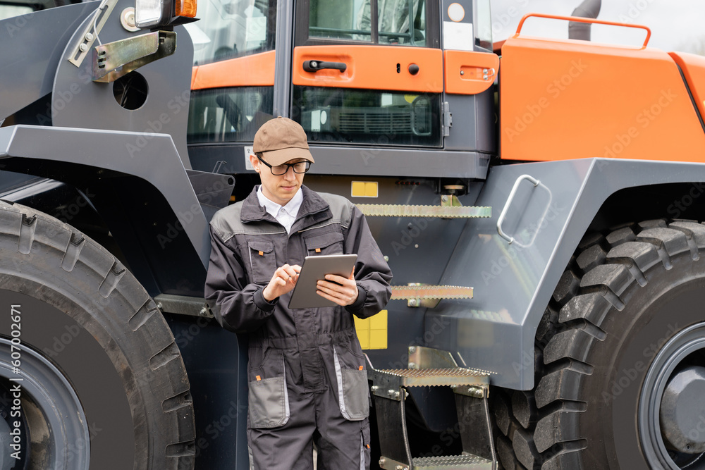 Poster serviceman with digital tablet on a background of the tractor