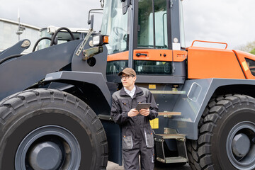 Serviceman with digital tablet on a background of the tractor	