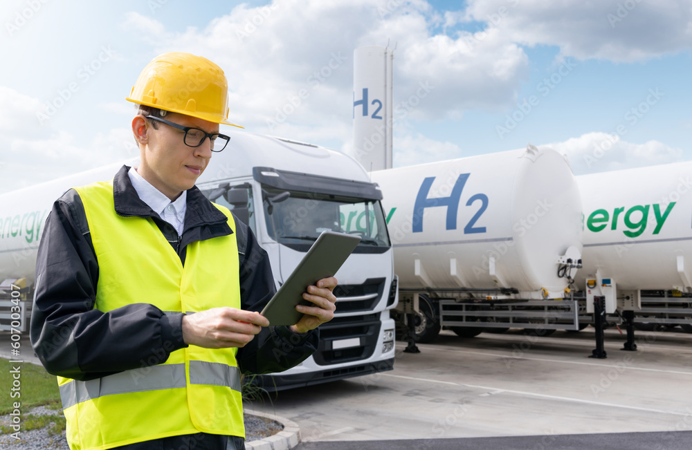 Wall mural Man with digital tablet on a background of hydrogen tank trailers