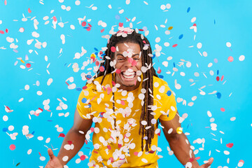 Happy latin man with dreadlocks surrounded by confetti in air