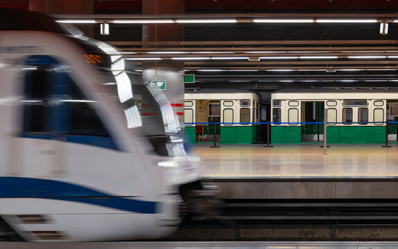 A subway train pulls into the underground station in Madrid. In the background is an old, historic subway.