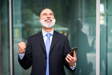 Very happy businessman holding his smartphone