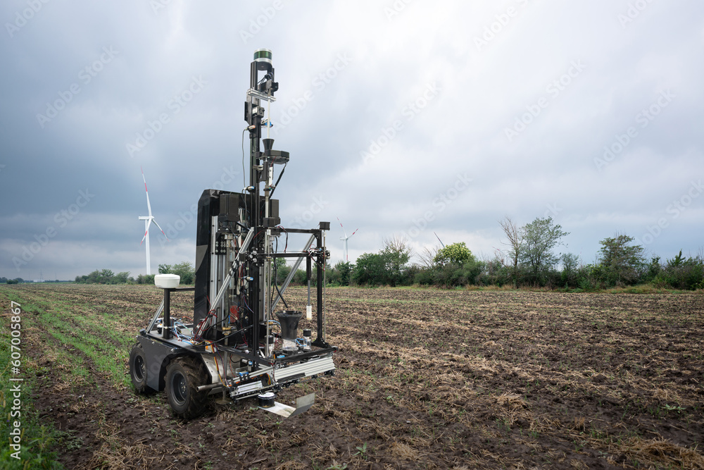 Poster autonomous robot for measuring soil quality in an agricultural field. wind turbine on a horizon. sma