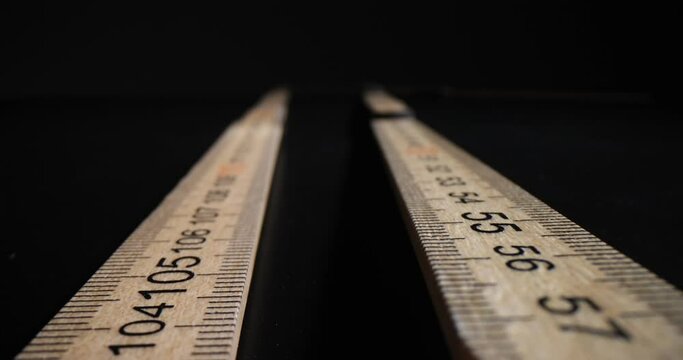 Long wooden ruler with digits and lines for measuring length. Centimeter tool prepared for measurement on black background. Building measuring instrument concept