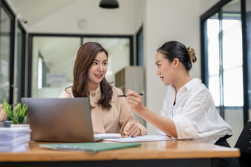 Two business women sit and discuss plans for a new project. Brainstorm and share ideas.